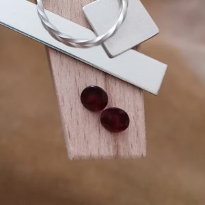 The red garnet rounds displayed on a jewellers bench peg with some sterling silver sheet and wire.