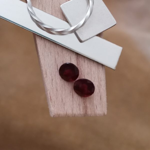 The red garnet rounds displayed on a jewellers bench peg with some sterling silver sheet and wire.