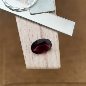 The purple-red garnet oval displayed on a jewellers bench peg with some sterling silver sheet and wire.
