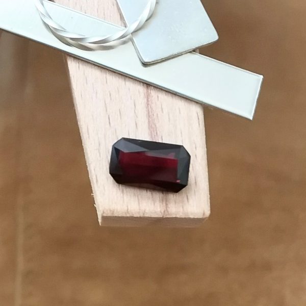 The red garnet rectangle displayed on a jewellers bench peg with some sterling silver sheet and wire.