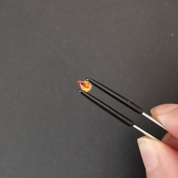 A photo of the crown area of the orange garnet against a black background