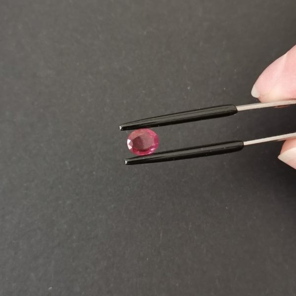 A photo of the crown area of the dark pink garnet against a black background