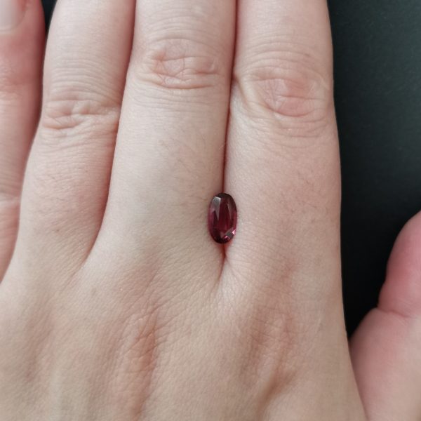 The pink garnet gemstone resting on a hand to give an idea of the gemstone size and colour.