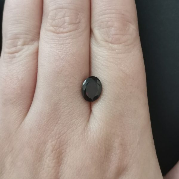The deep red garnet gemstone resting on a hand to give an idea of the gemstone size and colour.