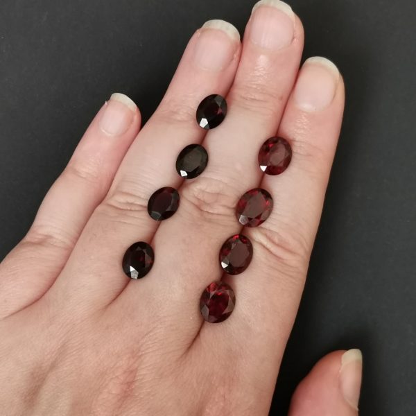 The red garnet gemstones resting on a hand to give an idea of the gemstone size and colour.