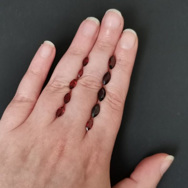 The red garnet gemstones resting on a hand to give an idea of the gemstones size and colour.