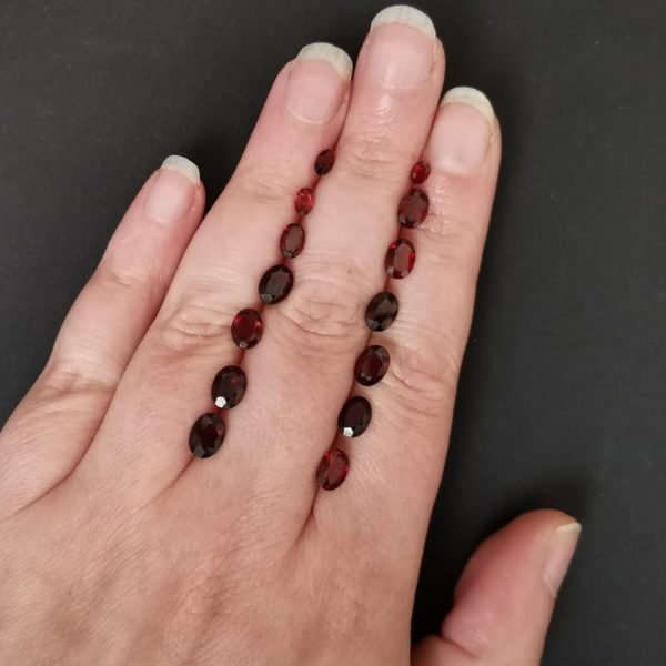 The red garnet gemstones resting on a hand to give an idea of the gemstone size and colour.