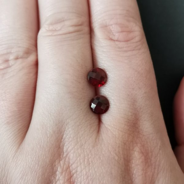 The red garnet gemstones resting on a hand to give an idea of the gemstone size and colour.