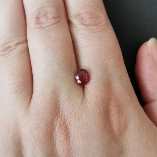 The pink garnet gemstone resting on a hand to give an idea of the gemstone size and colour.