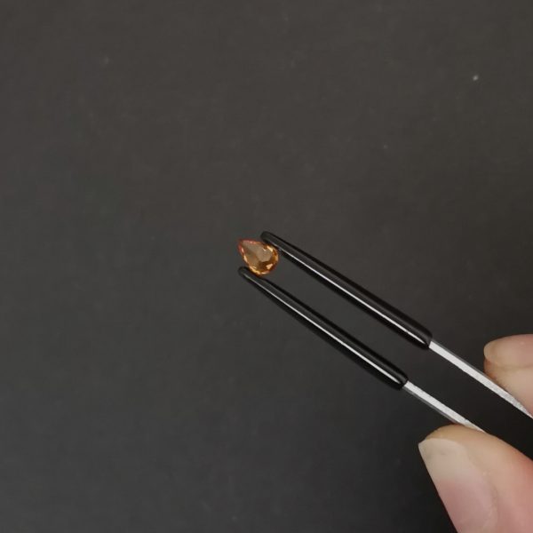 a photo of the pavilion of the orange hessonite garnet teardrop against a black background