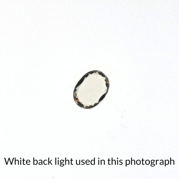 The yellow heliodor oval gem is being back-lit with a bright white light to show any inclusions within the gem more clearly.