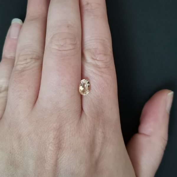 The golden yellow heliodor gemstone resting on a hand to give an idea of the gemstone size and colour.