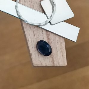 The blue-violet iolite oval displayed on a jewellers bench peg with some sterling silver sheet and wire.