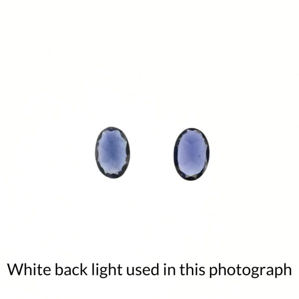 The blue-purple iolite oval gems are being back-lit with a bright white light to show any inclusions within the gems more clearly.
