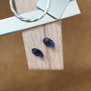 The pair of iolite ovals displayed on a jewellers bench peg with some sterling silver sheet and wire.