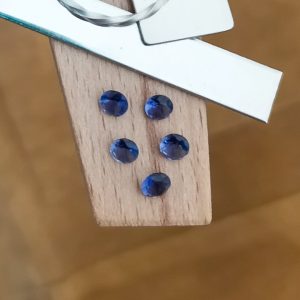 The bundle of iolite rounds displayed on a jewellers bench peg with some sterling silver sheet and wire.