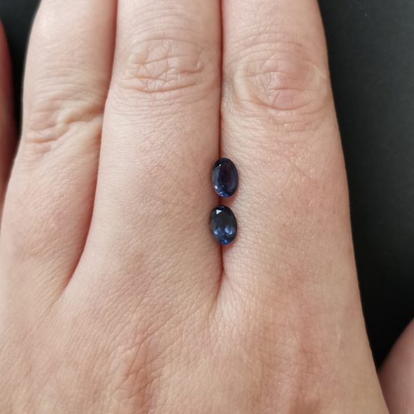 The pair of iolite gemstones resting on a hand to give an idea of the gemstone size and colour.