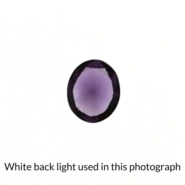 The purple lab grown sapphire oval gem is being back-lit with a bright white light to show any inclusions within the gem more clearly.