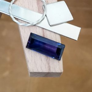 The purple lab grown sapphire displayed on a jewellers bench peg with some sterling silver sheet and wire.