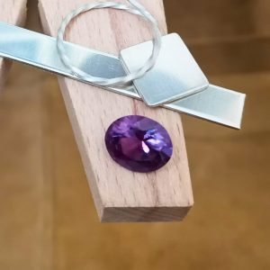 The purple lab grown sapphire oval displayed on a jewellers bench peg with some sterling silver sheet and wire.