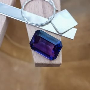 The purple lab grown sapphire displayed on a jewellers bench peg with some sterling silver sheet and wire.