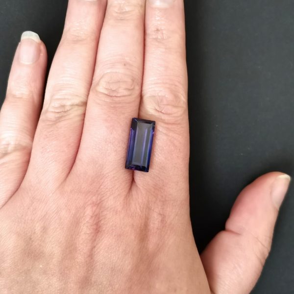 The purple lab grown sapphire gemstone resting on a hand to give an idea of the gemstones size and colour.