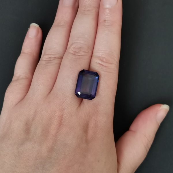 The purple lab grown sapphire gemstone resting on a hand to give an idea of the gemstone size and colour.