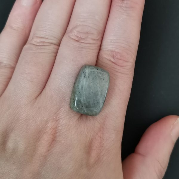 The labradorite cab resting on a hand to give an idea of the gemstones size and colour.
