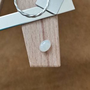 The opal cabochon displayed on a jewellers bench peg with some sterling silver sheet and wire.