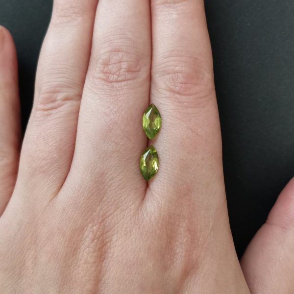 The green peridot gemstones resting on a hand to give an idea of the gemstone size and colour.