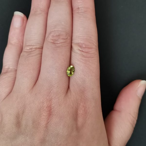 The green peridot gemstone resting on a hand to give an idea of the gemstone size and colour.