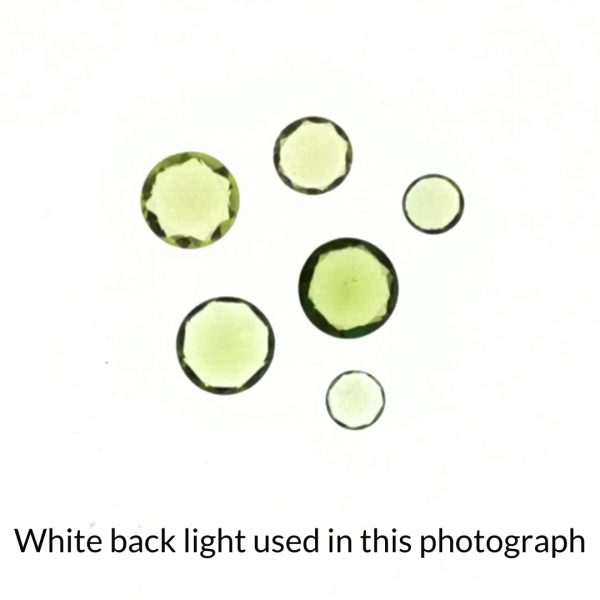 The round green peridot gems is being back-lit with a bright white light to show any inclusions within the gem more clearly.