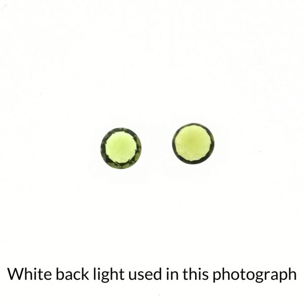 The peridot round gems are being back-lit with a bright white light to show any inclusions within the gems more clearly.