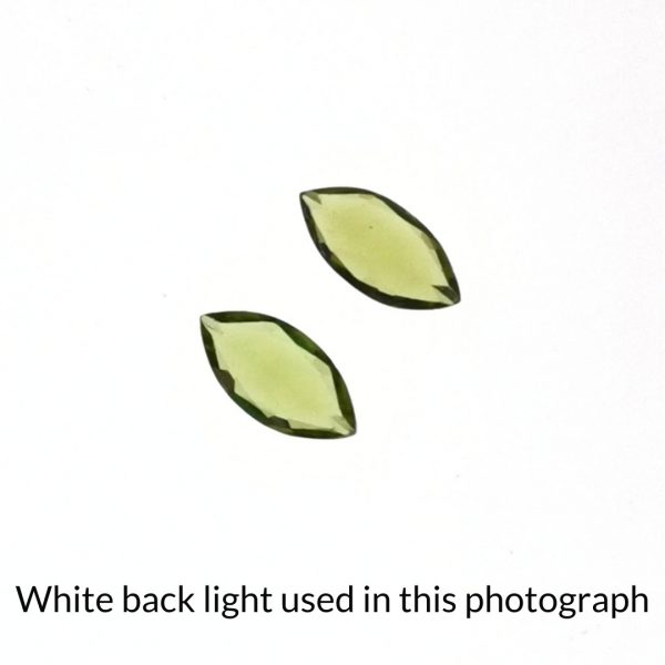 The peridot gems is being back-lit with a bright white light to show any inclusions within the gems more clearly.