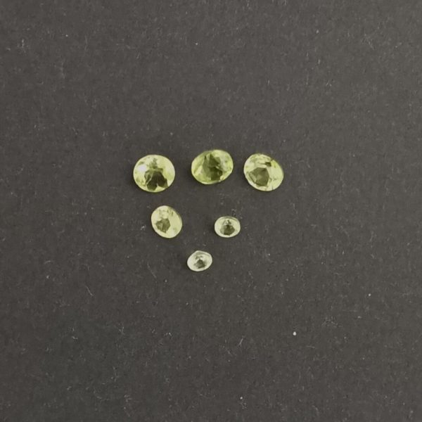 The bundle of 6 green peridot gemstones displayed on a black background