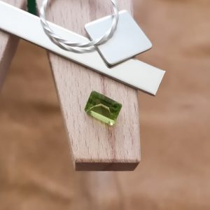 The peridot rectangle displayed on a jewellers bench peg with some sterling silver sheet and wire.