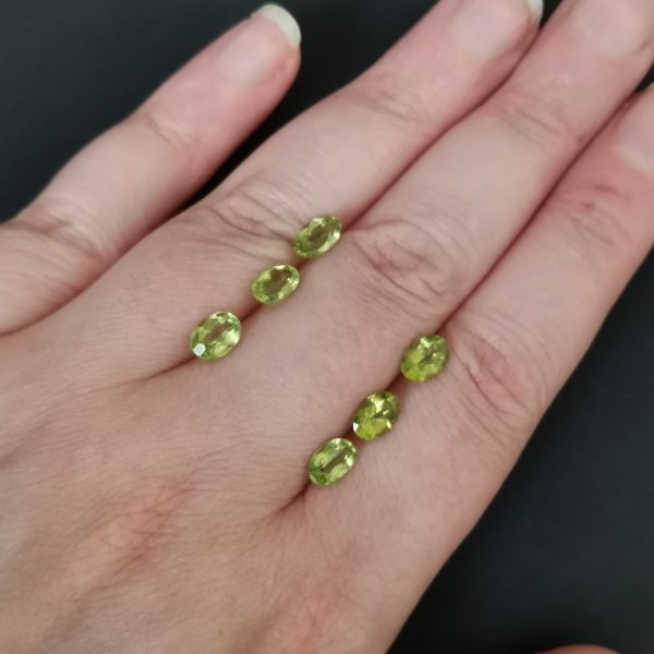 The green peridot gemstones resting on a hand to give an idea of the gemstones size and colour.