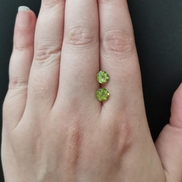 The peridot gemstones resting on a hand to give an idea of the gemstones size and colour.