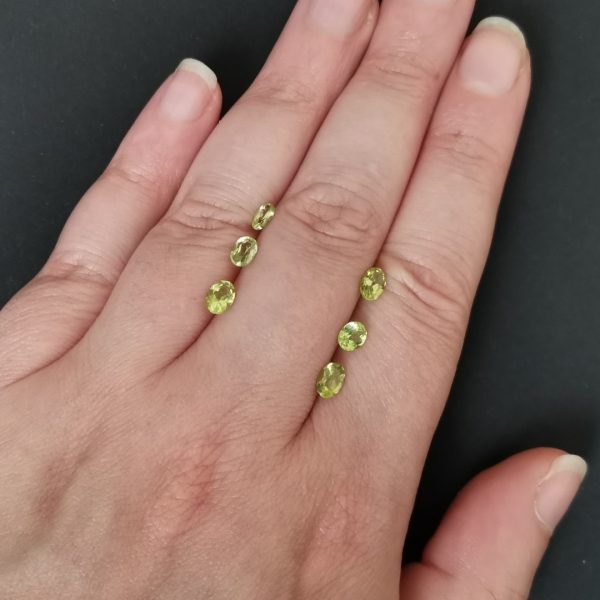 The green peridots gemstone resting on a hand to give an idea of the gemstone size and colour.