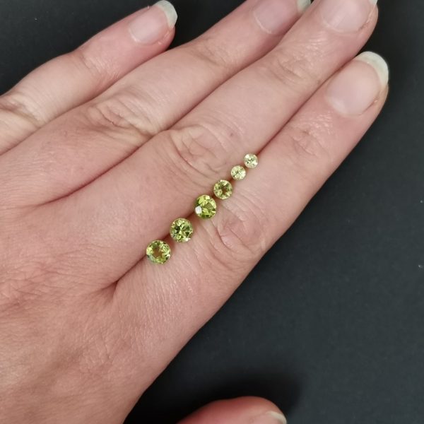 The green peridot gemstones resting on a hand to give an idea of the gemstones size and colour.