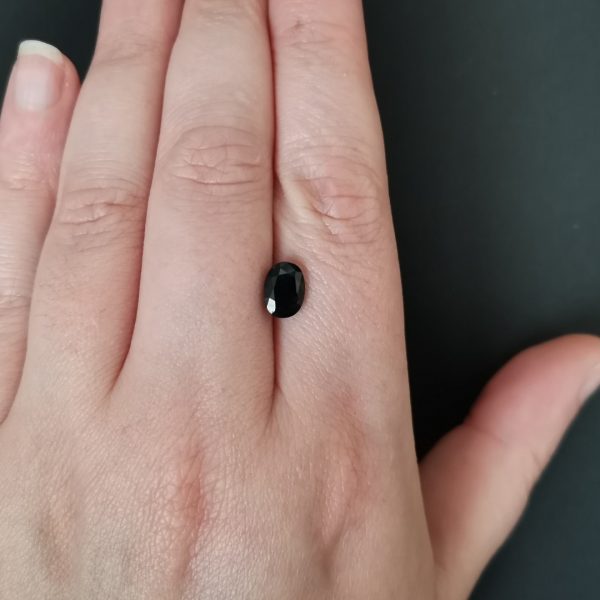 The blue and green sapphire gemstone resting on a hand to give an idea of the gemstone size and colour.