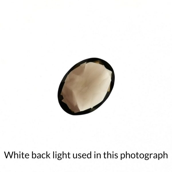 The brown smoky quartz oval gem is being back-lit with a bright white light to show any inclusions within the gem more clearly.