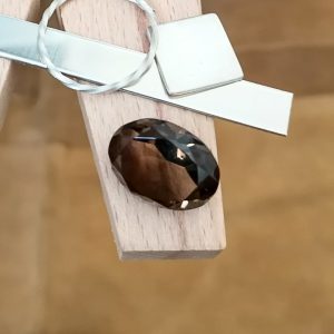 The brown smoky quartz oval displayed on a jewellers bench peg with some sterling silver sheet and wire.