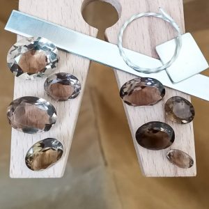 The bundle of smoky quartz ovals displayed on a jewellers bench peg with some sterling silver sheet and wire.