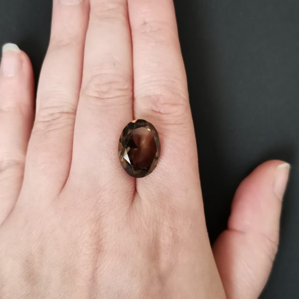 The brown smoky quartz gemstone resting on a hand to give an idea of the gemstone size and colour.