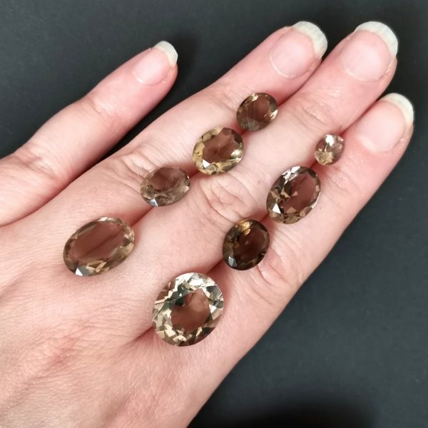 The bundle of 8 smoky quartz gemstones resting on a hand to give an idea of the gemstones size and colour.