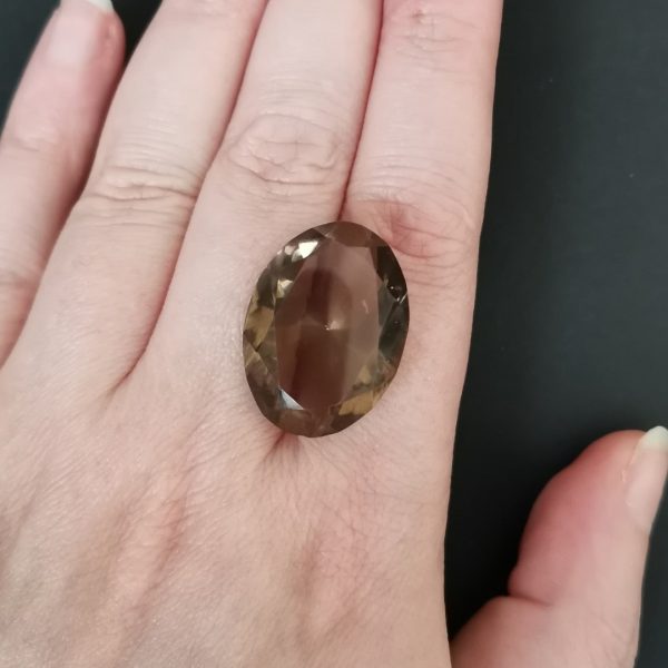 The brown smoky quartz gemstone resting on a hand to give an idea of the gemstones size and colour.