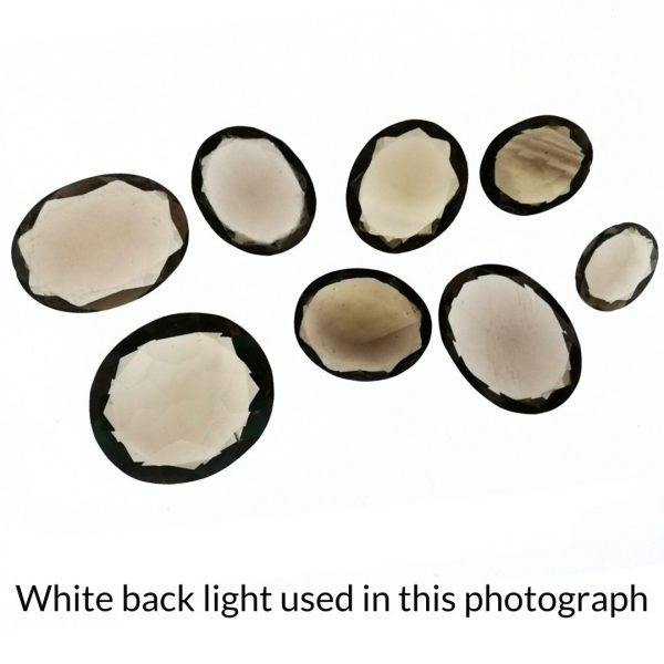 The brown smoky quartz oval gems are being back-lit with a bright white light to show any inclusions within the gem more clearly.