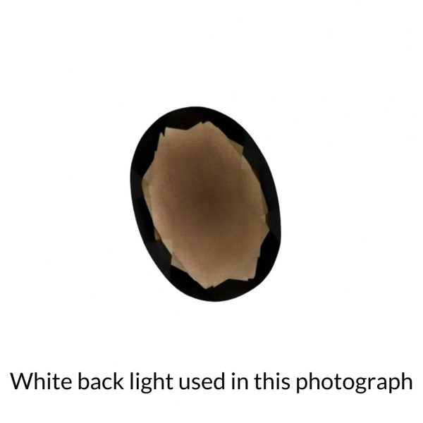 The brown smoky quartz oval gem is being back-lit with a bright white light to show any inclusions within the gem more clearly.