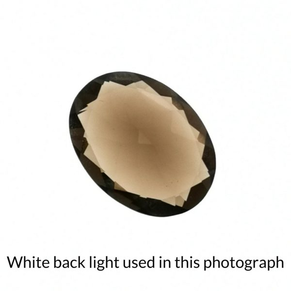 The brown smoky quartz oval gem is being back-lit with a bright white light to show any inclusions within the gem more clearly.